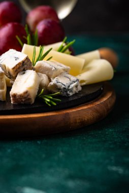 Bir bardak şarap, değişik türde yumuşak peynir ve üzümler.