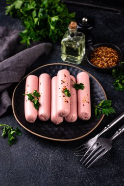 Arka planda baharatlı haşlanmış domuz sosisi.