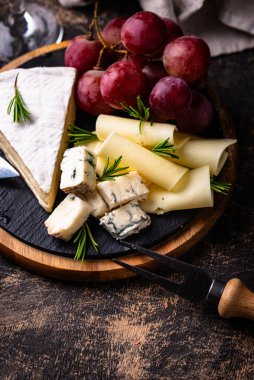 Bir bardak şarap, değişik türde yumuşak peynir ve üzümler.