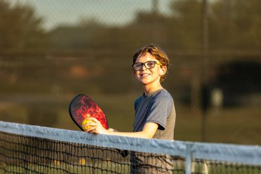 Pickleball teçhizatı olan genç çocuk sahada.