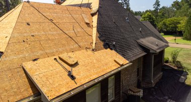 House with new roof being installed after hail damage clipart