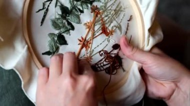 Kadın eli kapalı, iplik ve iğneyle nakış işliyor.