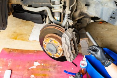 Tamirci aracın fren pedlerini değiştirmeye çalışıyor..