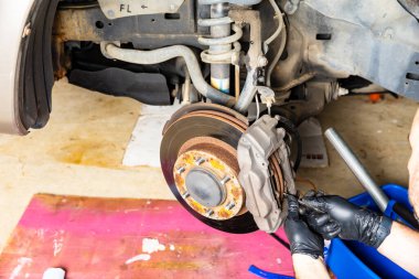 Tamirci aracın fren pedlerini değiştirmeye çalışıyor..