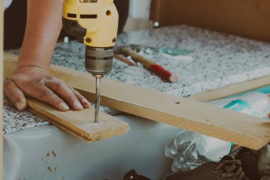 Adam yerde bir matkapla çalışıyor.