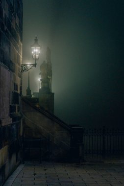 Illuminated lamp in fog on Charles Bridge, Prague at night, cast clipart