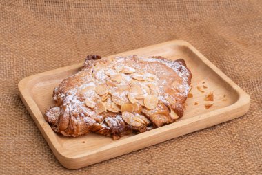 Tahta kesme tahtasındaki badem kruvasanları beyaz mermer arka planda