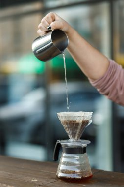 Bir hunide kahve yapmak. Funnel 'deki kahvenin üzerine dök. Alternatif Yöntem. Koyu arkaplanı olan güzel bir masa. Kahve spesiyalitesini demleme süreci. Kahve dökülüyor.