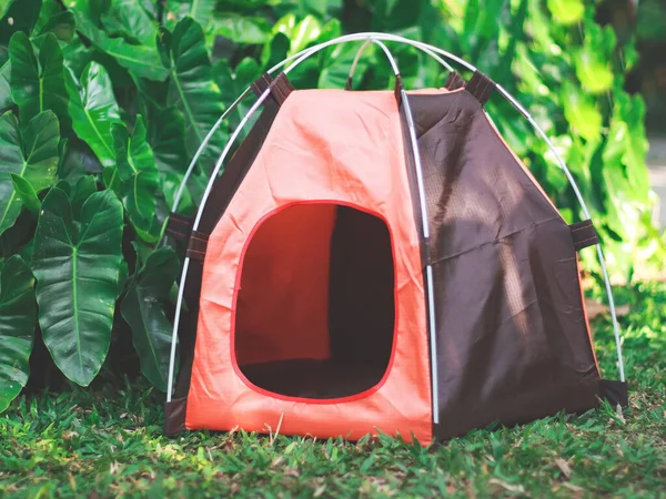 Front view of empty orange pet camping tent in the garden.