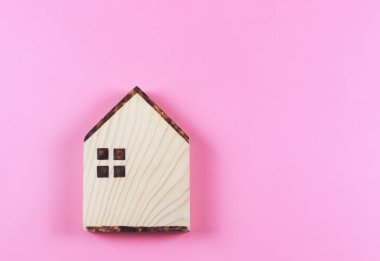 Top view or flat lay of wooden model house on pink background.