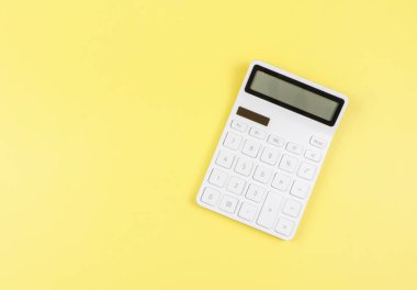 Top view or flat lay of white  calculator on yellow  background with copy space.