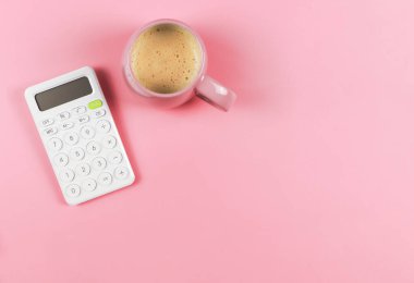 Üst görünüm ya da düz beyaz hesap makinesi yatağı ve pembe arka planda fotokopi alanı olan pembe kahve fincanı.
