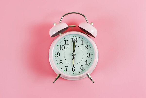Вид сверху или плоский слой розового винтажного будильника показывает 6 часов на розовом фоне с копировальным пространством.
