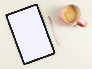 Beyaz ekran, pembe stilus kalem ve beyaz arka planda izole edilmiş pembe kahve fincanı olan dijital tabletin üst görünümü veya düz yatağı.