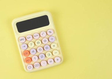 Sarı arkaplanda, kopyalama alanı olan renkli hesap makinesinin üst görünümü veya düz yatağı.