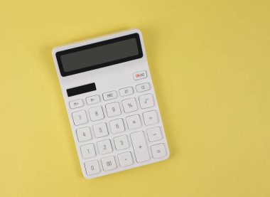 Top view or flat lay of white  calculator on yellow  background with copy space.