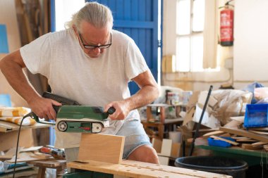 Çalışma alanında ahşap işçiliği üzerine çalışan usta marangoz, profesyonel aletlerle ahşap mobilyalar üretiyor. Yüksek kalite fotoğraf