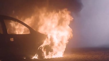 Yanan araba ağır çekim. Araba tekerleği yanıyor. Arabayı ateşe verin. Yüksek kalite 4k görüntü