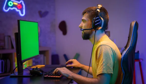 ゲームホームスタジオで緑の画面のモックアップ表示とプロゲーマーストリーミングビデオゲーム クロマキー ヘッドセットを身に着けているRgbプロのコンピュータ孤立デスクトッププレイシューティングゲームを使用してプレーヤー — ストック写真