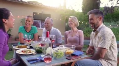 Mutlu arkadaşlar bir yaz lokantasında masanın etrafında sırıtarak gülüyorlar. Ev verandasında yemek yerken gülümseyen insanlar. Gülümseme, neşe konsepti. Yüksek kalite fotoğraf