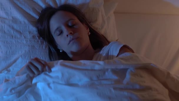 美丽的女孩打开灯 与来自月亮的蓝色色彩一起睡在床上 4K慢动作红外摄像机视频 高质量的录像 — 图库视频影像