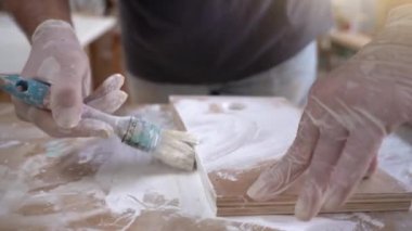 Sanatçı ressamın, atölyede ahşap mobilyaları yavaş çekimde boyamasına yakın çekim. Yüksek kalite 4k görüntü