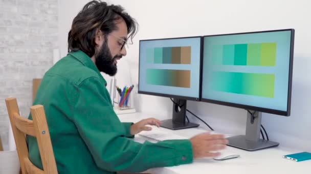 彼のコンピュータとデジタルタブレットで現代のホームオフィスで作業グラフィックデザイナー 作業ツールとサンプルカラースウォッチカタロググラデーションを使用して創造的な建築家 高品質4Kビデオ映像 — ストック動画