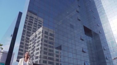 Modern bir binanın önünde akıllı telefonuyla konuşan mutlu çekici bir iş kadını. Yüksek kalite fotoğraf