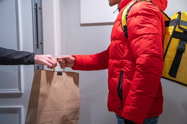 Unrecognizable food delivery man delivers bag of food to a customer who has ordered online. High quality photo