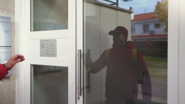Yemek teslimatçısı bir evin kapısına vardığında zili çalar ve daireye girer. Yemek teslimatı konsepti. Yüksek kalite 4k görüntü