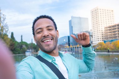 Attractive latin man taking a selfie looking at camera smiling. Happy student tourist traveling around the world in Erasmus.