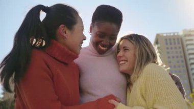 Three female friends affectionately hug each other having fun together laughing happy smiling. Collective lovely embrace concept. High quality 4k footage
