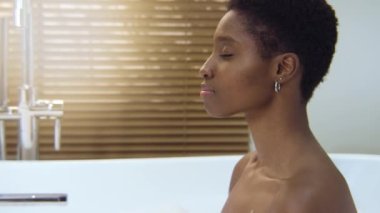 Attractive woman relaxing in foam luxury bath during a sunny morning routine. Rest and joy concept. 4k shot on RED camera slow motion.
