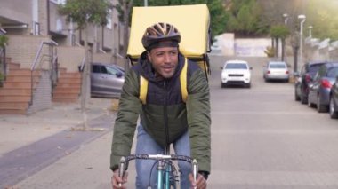 Black courier delivering food and drink in town outdoors on stylish bicycle in slow motion. Delivery man riding on bike with backpack. High quality 4k footage