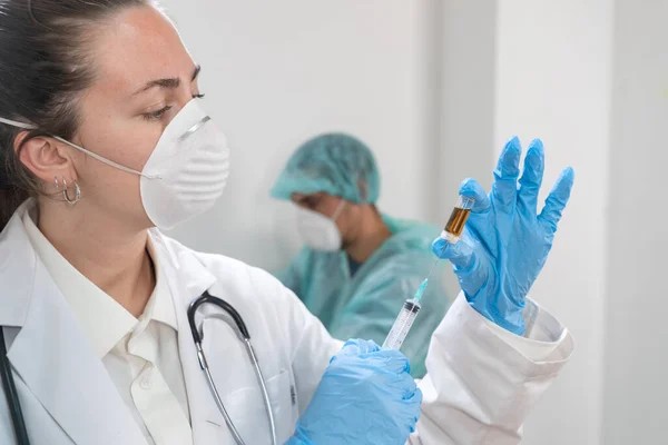 매력적 여의사가 예방용 마스크와 푸른색 장갑을 주사기를 준비하고 코로나 바이러스 — 스톡 사진