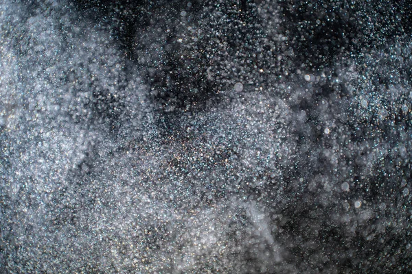 Dust particles cloud generating abstract shape on black background with copy space for text, web, design or banner.