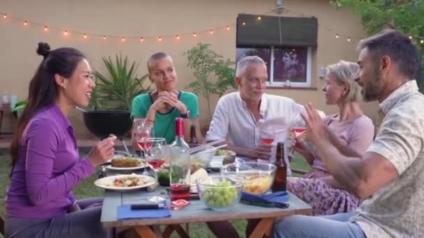 裏庭の外のディナーバーベキューで幸せな友人が食べて飲んでいます 週末に成熟した中年の人々 高品質の写真 — ストック動画