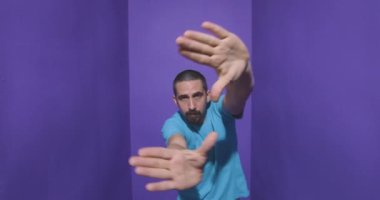 Adam çerçeveyi elleri ve parmaklarıyla yapıyor, mor arka planda izole edilmiş. Yüksek kalite 4k görüntü