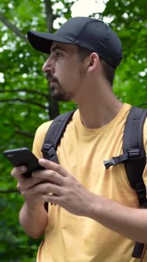 Ormanda sırt çantalı bir adam bağlantı sinyali aramak için telefon kullanıyor. Yüksek kaliteli FullHD görüntüler