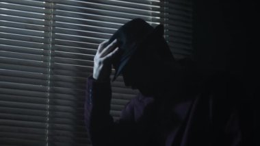 Casus film karakteri kara filmlerde şapka takar. Pencerenin arkasındaki arka ışığın yanındaki karanlık oda. Yüksek kalite 4k görüntü