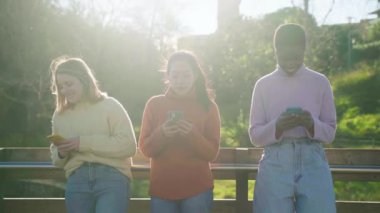 Cheerful female friends using cell phones and walking in the city. Technology addicted millennial community concept. Social Media communication generation Z. High quality photo