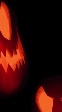 Cadılar Bayramı balkabağı suratlı, siyah arka planda mum ışığı uçuşan ürkütücü yüzler. Turuncu korkunç Jack O Lantern 4K. Yüksek kalite 4k görüntü
