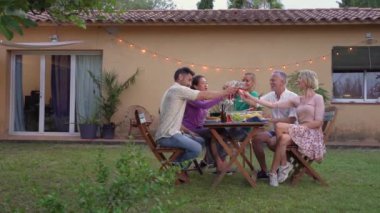 Bir grup neşeli arkadaş, Veranda Lokantası 'nda masanın etrafında gülücüklerle kadeh kaldırıyor. Yüksek kalite fotoğraf