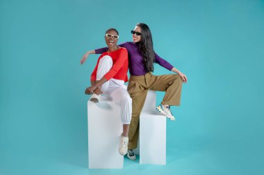 Stüdyonun mavi arka planında güneş gözlüklü iki çekici kadın. Yüksek kalite fotoğraf