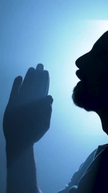  Karanlık uzayda kutsal bir ışıkla dua eden bir adamın silüeti. Yüksek kalite 4k görüntü