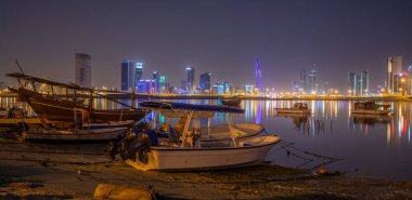 Basra Körfezi kıyısında arka planda Manama, Bahreyn 'de ışıklandırılmış motorlu tekneler.