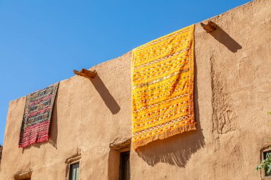 Geleneksel çamur evlerinin çatısından sarkan süslü Arap halıları, El Ula, Medine, Suudi Arabistan