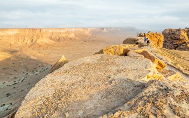 Çölün aşağısındaki Jabal Tuwaiq Dağları ve uzaktaki turist grubu Riyad, Suudi Arabistan