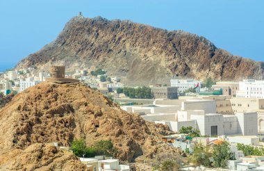 Muscat Takia tarihi şehir merkezi caddeleri arka planda kayalar ve ortaçağ kulesi olan manzara manzarası, Umman.