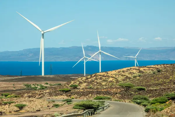 stock image The Ghoubet wind power turbines generators of grid station farms standing at the sea with road in foreground, Arta Region, Djibouti